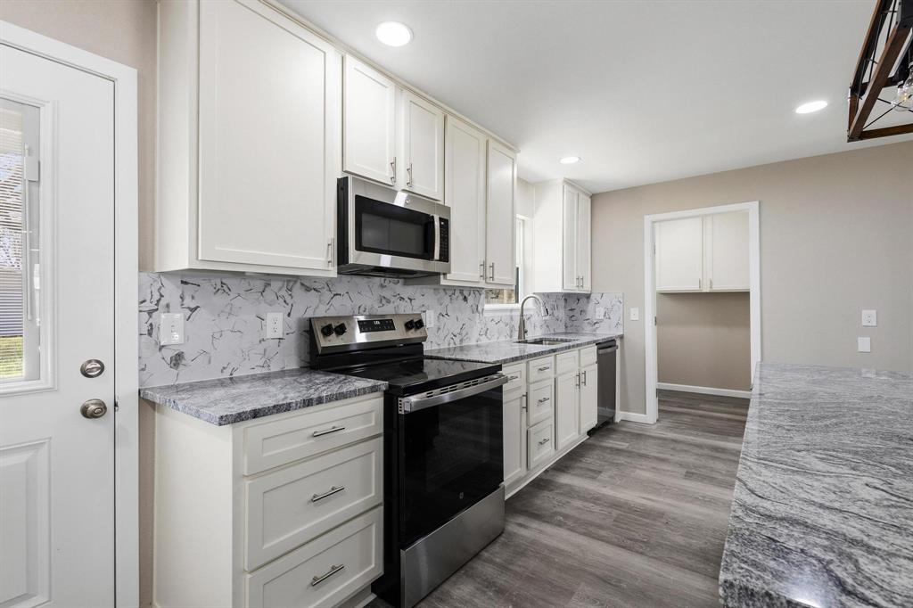 1704 Harris Street Gainesville, TX 76240 - Photo 9 of 21 Kitchen featuring stainless steel appliances, light stone countertops, white cabinetry, dark wood-style floors, and recessed lighting