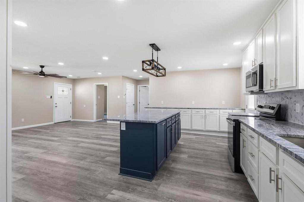 1704 Harris Street Gainesville, TX 76240 - Photo 10 of 21 Kitchen with stainless steel appliances, two tone cabinets, hanging light fixtures, light stone countertops, and tasteful backsplash