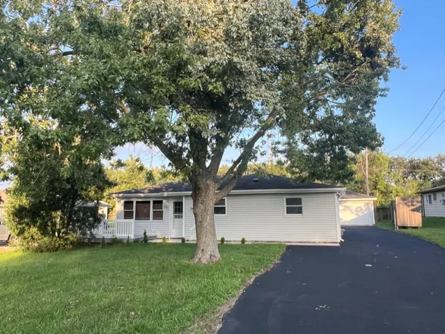 a front view of a house with a garden and trees
