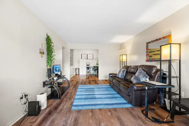 a living room with furniture a wooden floor and next to a window