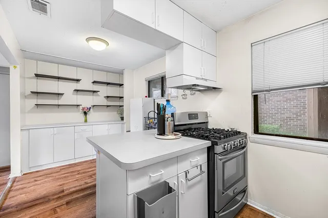 a kitchen with stainless steel appliances a white cabinets and wooden floor