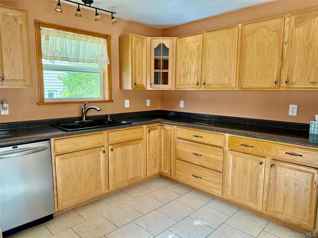 a kitchen with granite countertop white cabinets sink and a large window