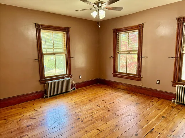 an empty room with wooden floor chandelier and windows