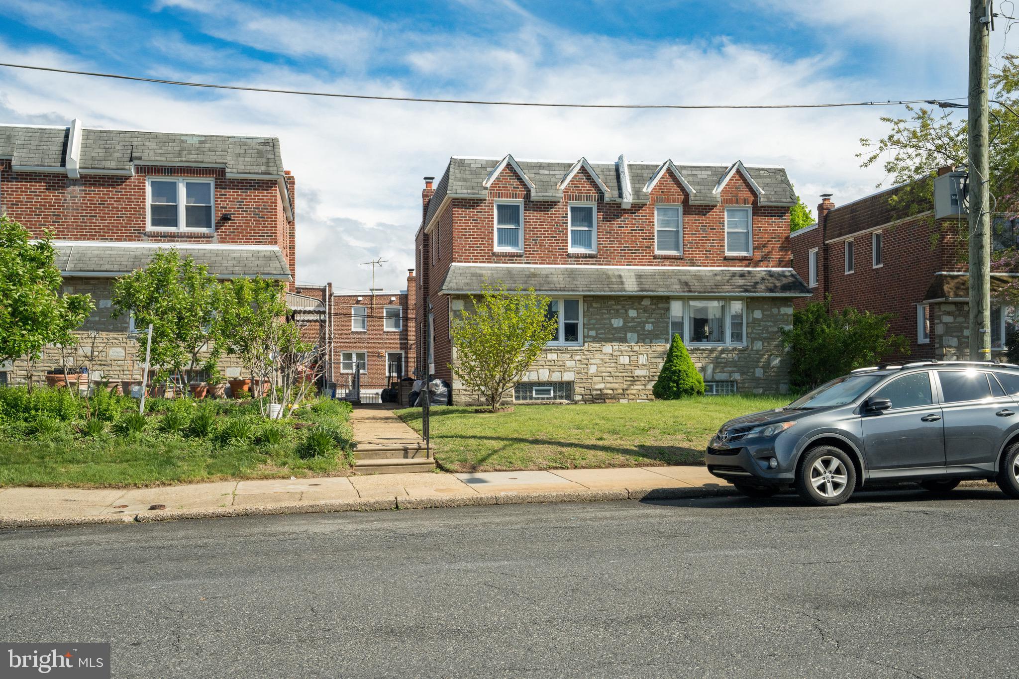 a front view of a house with a garden and parking
