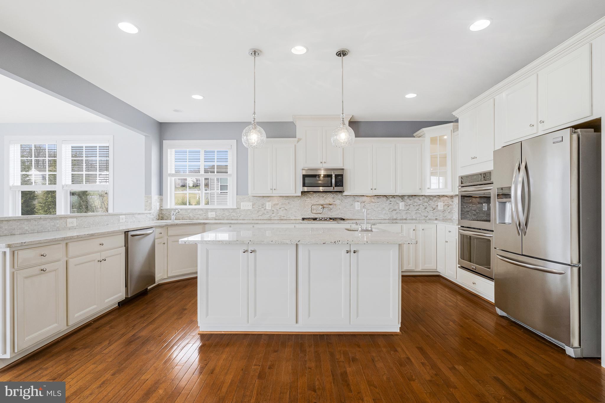 41729 Wakehurst Place Leesburg, VA 20176 - Photo 21 of 71 a kitchen with stainless steel appliances granite countertop a refrigerator a sink dishwasher a stove and white cabinets with wooden floor