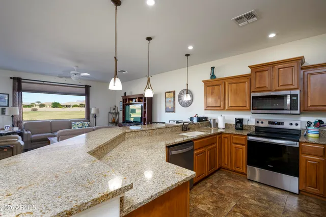a kitchen with stainless steel appliances granite countertop a sink a stove and a wooden floors