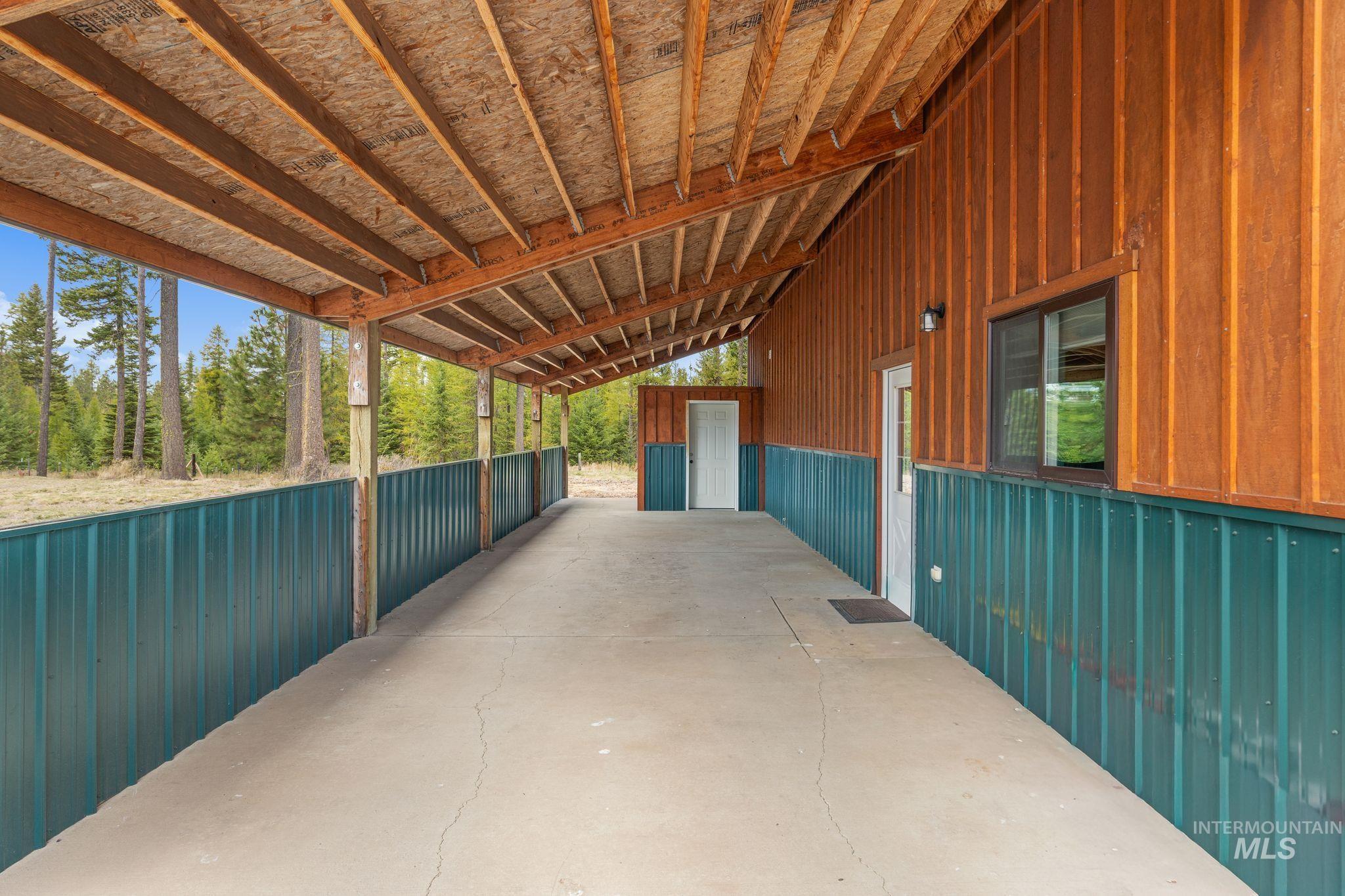 3989 East Mountain Road Anatone, WA 99401 - Photo 37 of 49 Covered exterior corridor with concrete flooring, wood-paneled walls, and a metal roof