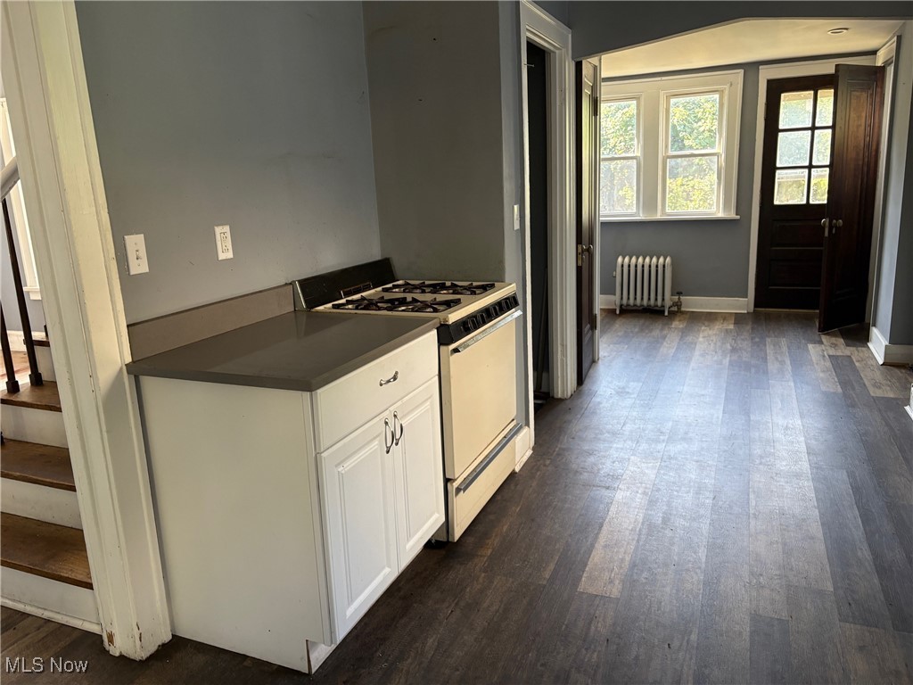 3258 Berkshire Road Cleveland, OH 44118 - Photo 14 of 23 Kitchen featuring white gas range, dark wood finished floors, radiator heating unit, dark countertops, and white cabinets
