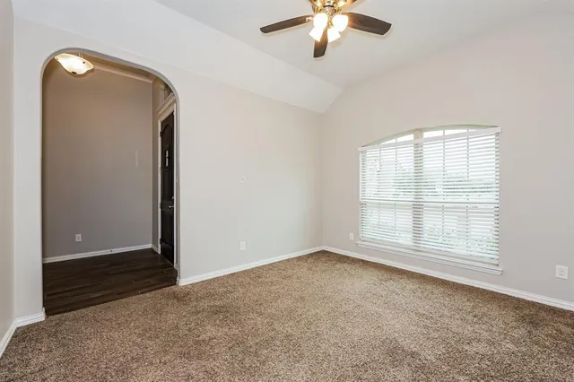 an empty room with chandelier fan and windows
