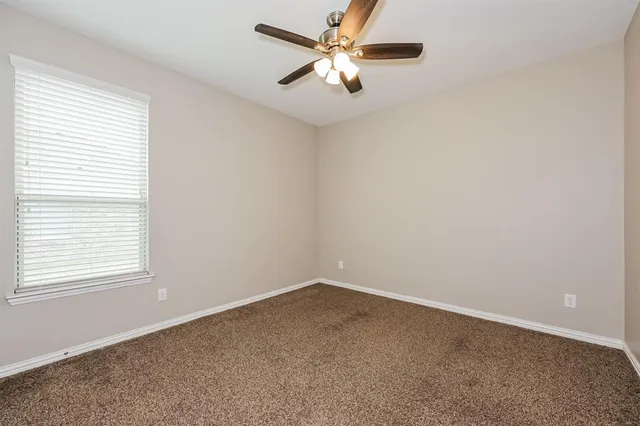 an empty room with a window and a fan
