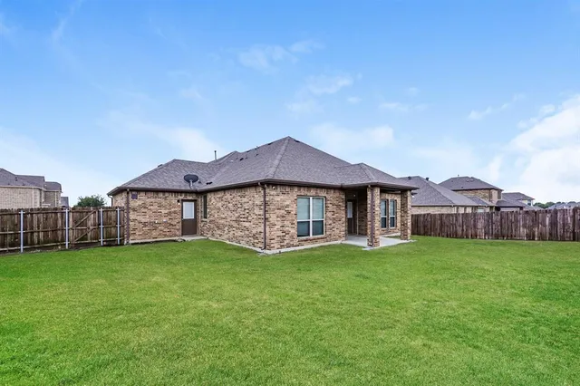 a view of a house with a yard and a large tree