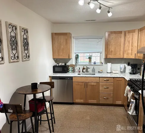a kitchen with granite countertop a stove a sink cabinets and a dining table