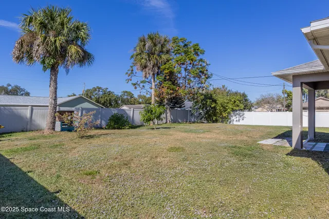 a view of a house with a yard and palm tree