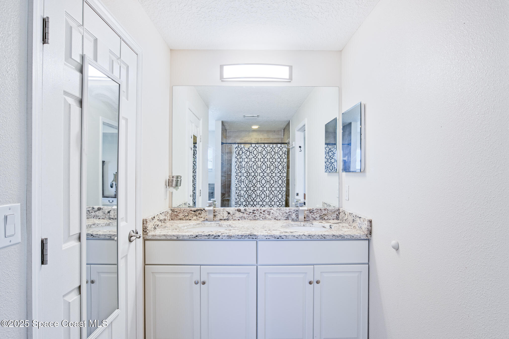7350 Barbara Road Cocoa, FL 32927 - Photo 7 of 26 a bathroom with a granite countertop sink a mirror and a shower
