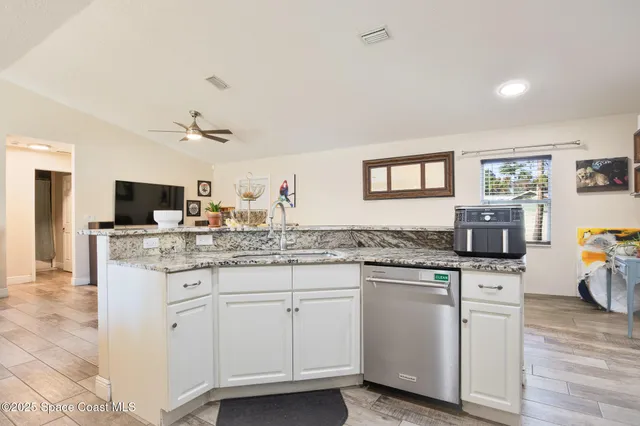 a kitchen with granite countertop a sink and white cabinets