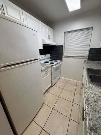 a kitchen with granite countertop white cabinets and white appliances