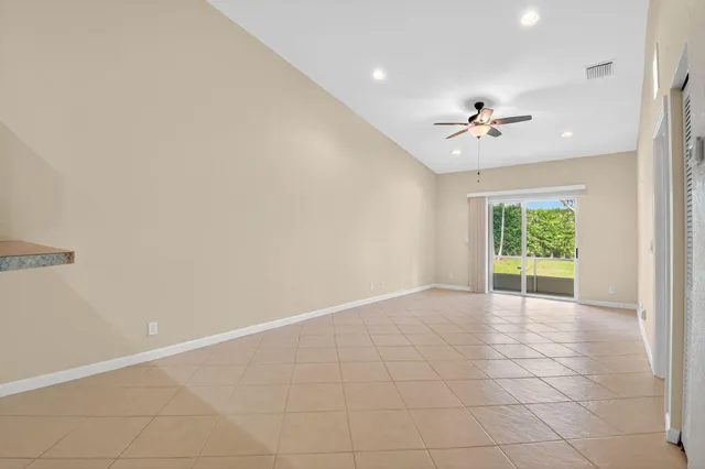 an empty room with a kitchen and a chandelier fan