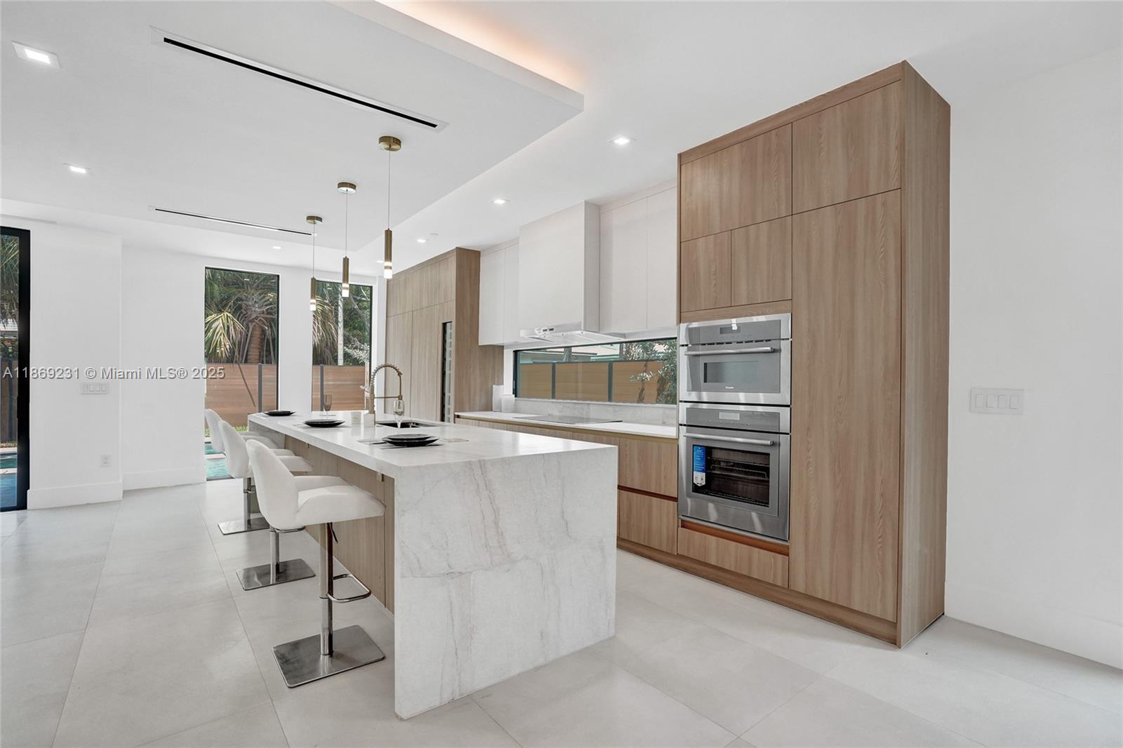 1825 Northeast 26th Avenue, Unit C Fort Lauderdale, FL 33305 - Photo 25 of 90 a kitchen with kitchen island a large counter top space a sink stainless steel appliances and cabinets