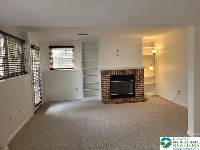a view of an empty room with a fireplace and a window