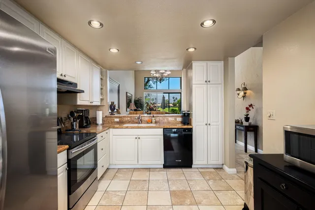 a large kitchen with stainless steel appliances granite countertop a refrigerator and a sink