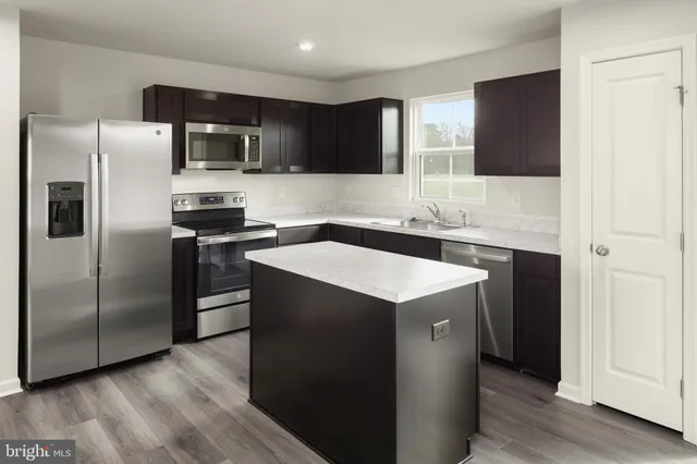 a kitchen with stainless steel appliances a sink a stove a refrigerator and cabinets