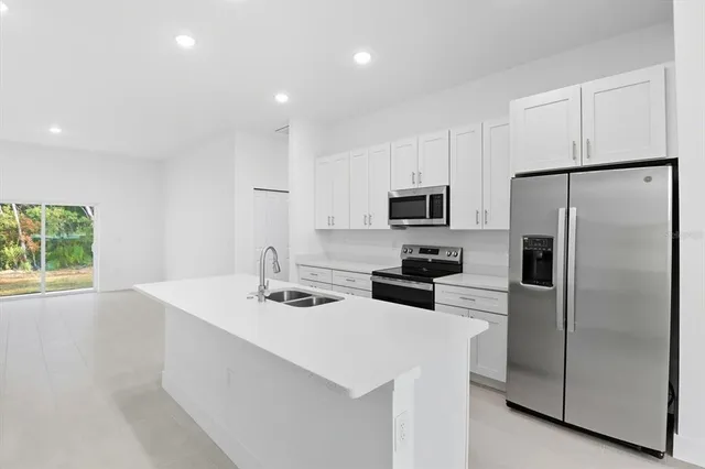 a kitchen with kitchen island a sink stainless steel appliances and white cabinets