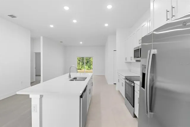a view of a kitchen with a sink refrigerator and wooden floor