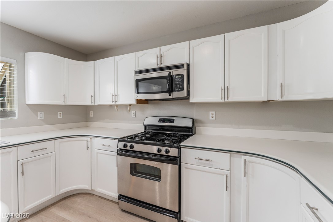 3695 Funston Way Las Vegas, NV 89129 - Photo 7 of 43 Kitchen with appliances with stainless steel finishes, white cabinetry, light countertops, and light wood-style flooring