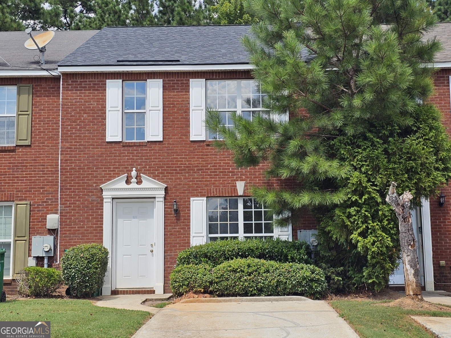 a front view of a house with a yard and trees