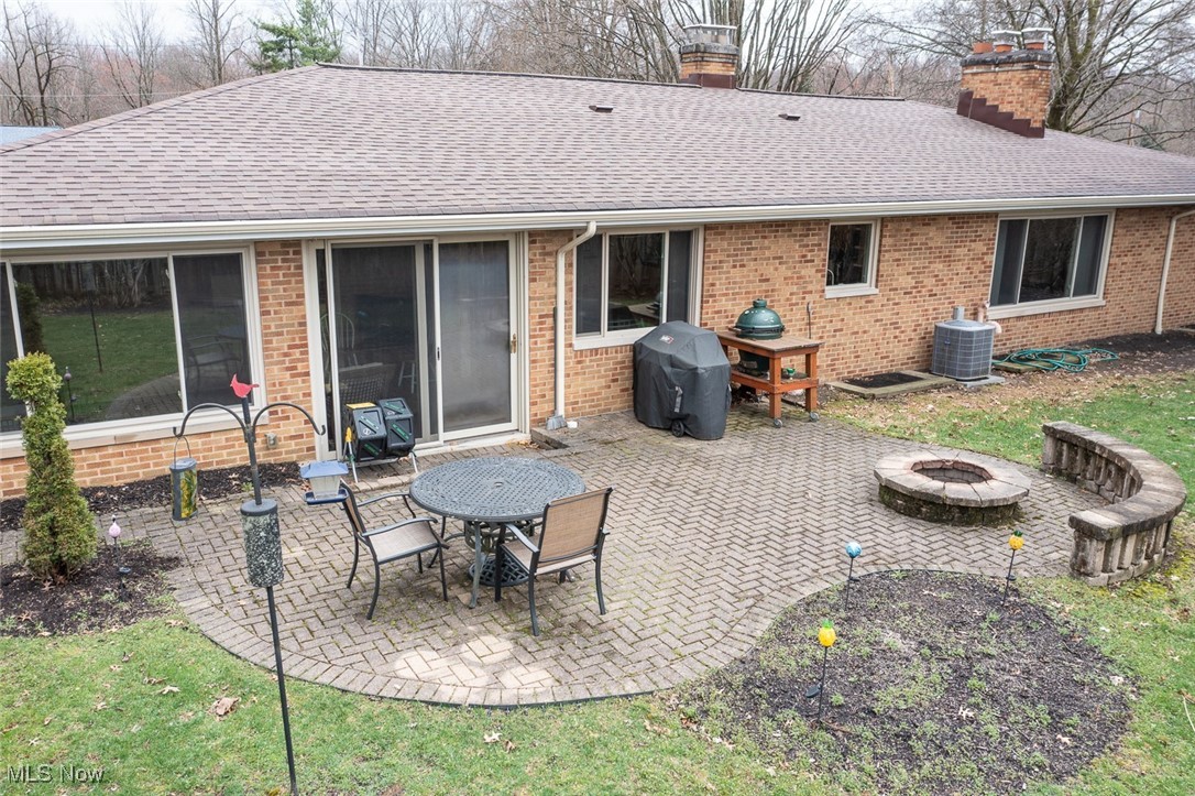 13740 Old Pleasant Valley Road Cleveland, OH 44130 - Photo 28 of 28 Rear view of property featuring central AC unit, a shingled roof, a patio, and brick siding. Firepit in paver area.