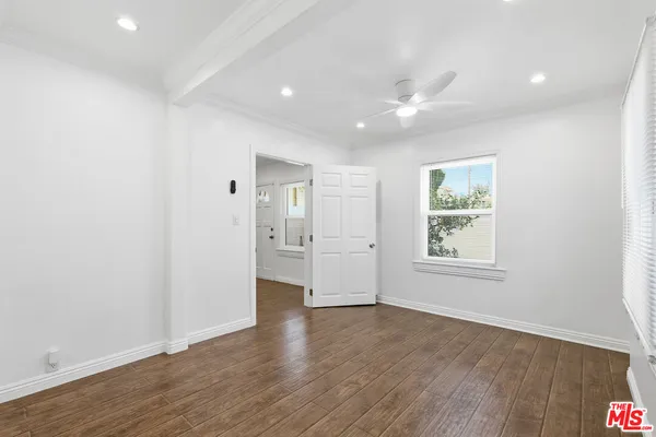 a view of an empty room with wooden floor and windows