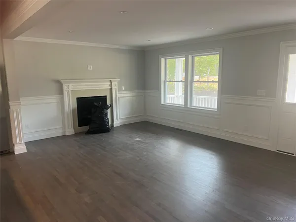 an empty room with wooden floor fireplace and windows