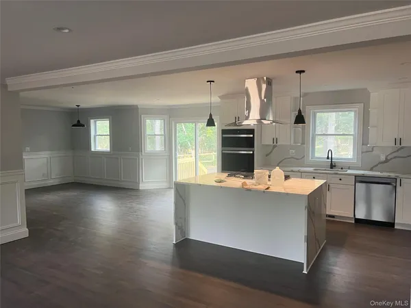 a kitchen with kitchen island granite countertop a sink cabinets and wooden floor