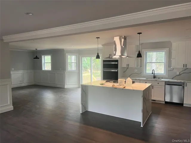 a kitchen with kitchen island granite countertop a sink cabinets and wooden floor