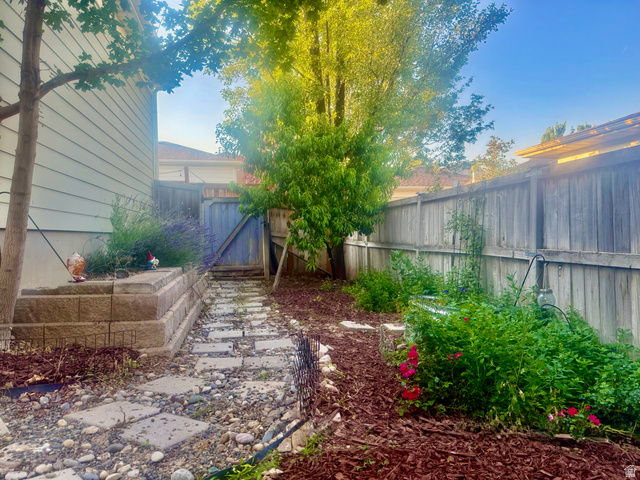 11751 Lake Run Road South Jordan, UT 84009 - Photo 34 of 38 Backyard featuring wood fencing, mature trees, a retaining wall, and a stone path