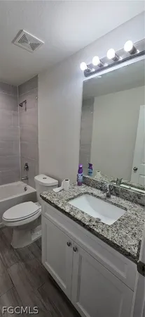 a bathroom with a granite countertop toilet a sink and a mirror