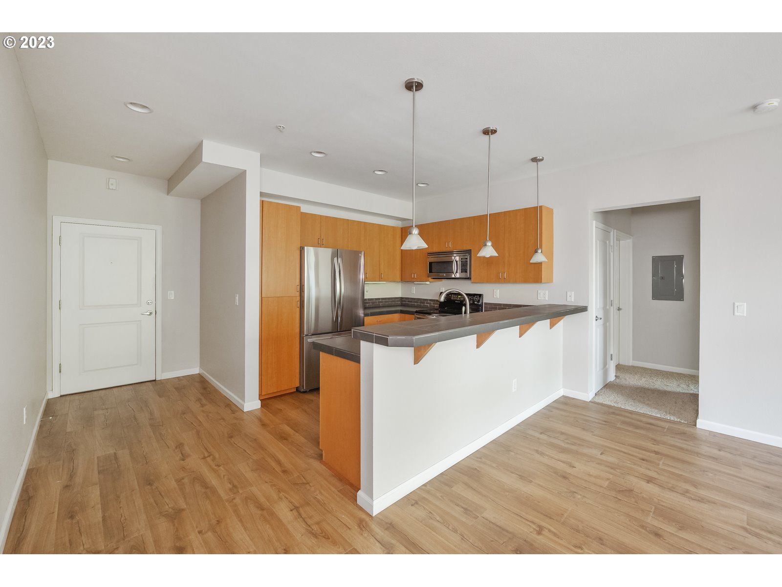 8712 North Decatur Street, Unit 201 Portland, OR 97203 - Photo 13 of 40 a kitchen with stainless steel appliances granite countertop a refrigerator a sink dishwasher a stove and white cabinets with wooden floor