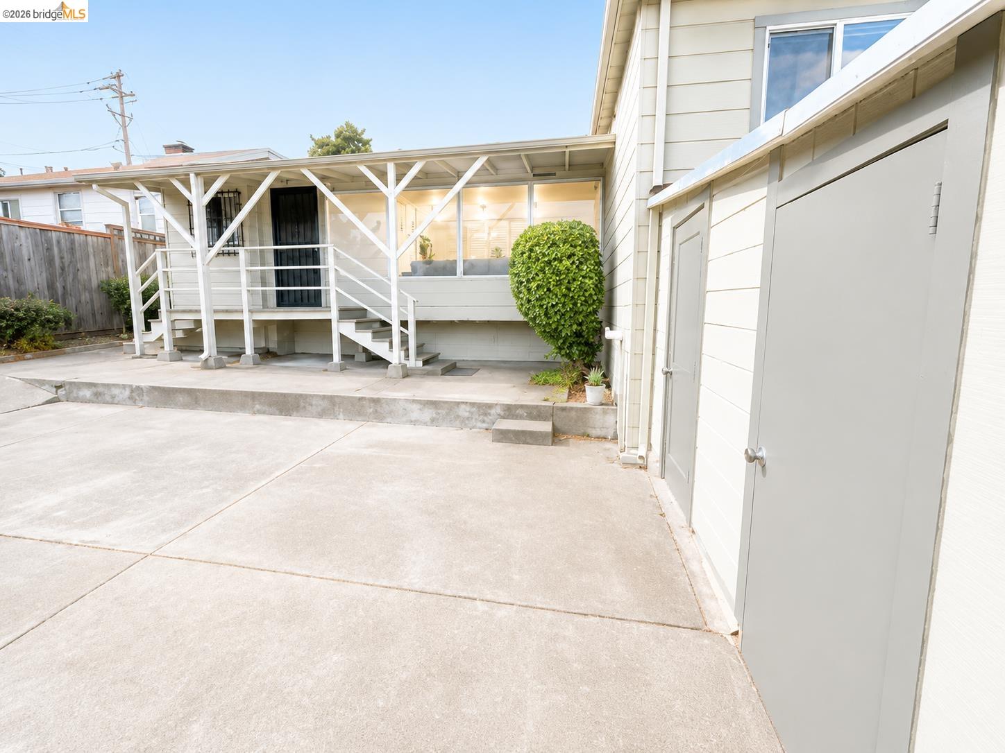 810 Pierce Street Albany, CA 94706 - Photo 22 of 25 Concrete patio area featuring a covered porch with white railing, exterior staircase, and multiple exterior storage units