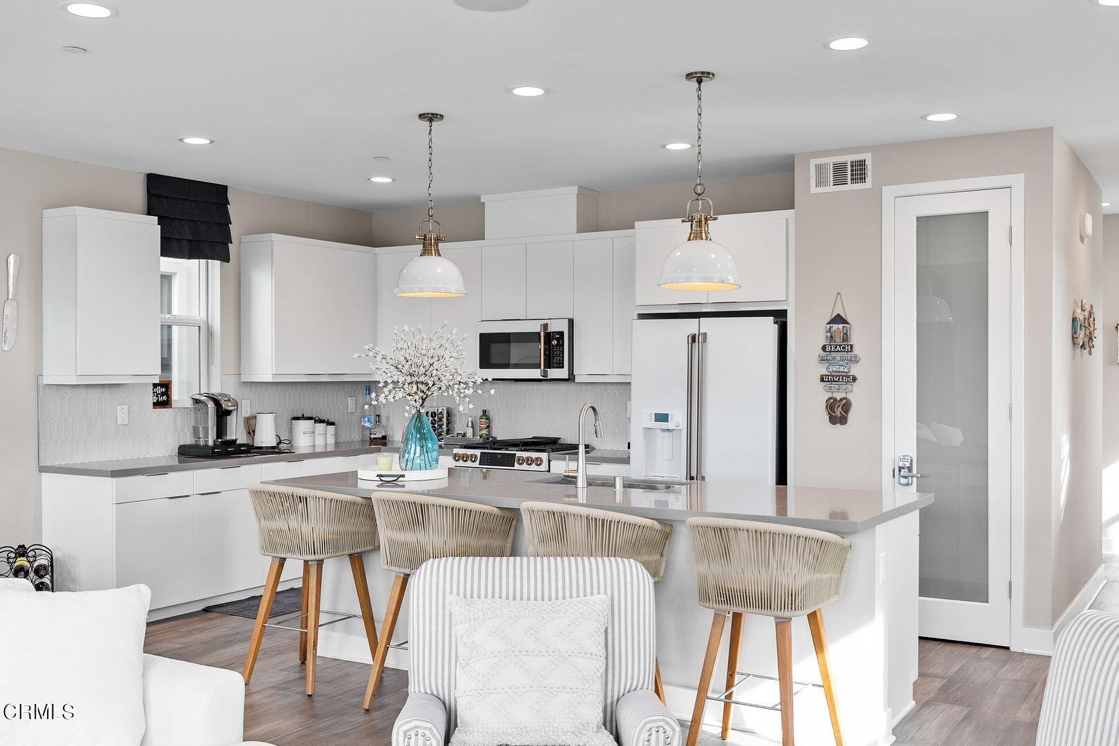 1028 Harbor Boulevard Oxnard, CA 93035 - Photo 29 of 48 a kitchen with stainless steel appliances kitchen island granite countertop a table chairs refrigerator and microwave