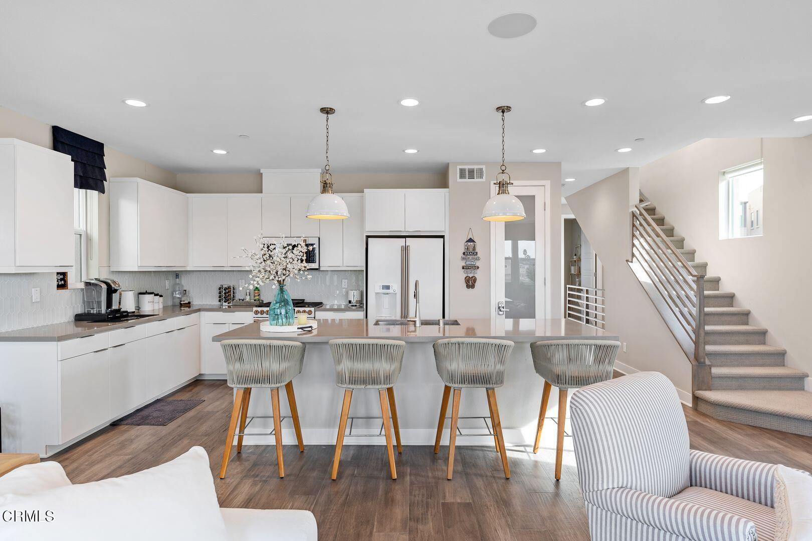 1028 Harbor Boulevard Oxnard, CA 93035 - Photo 3 of 48 a kitchen with stainless steel appliances kitchen island granite countertop a dining table chairs sink and white cabinets