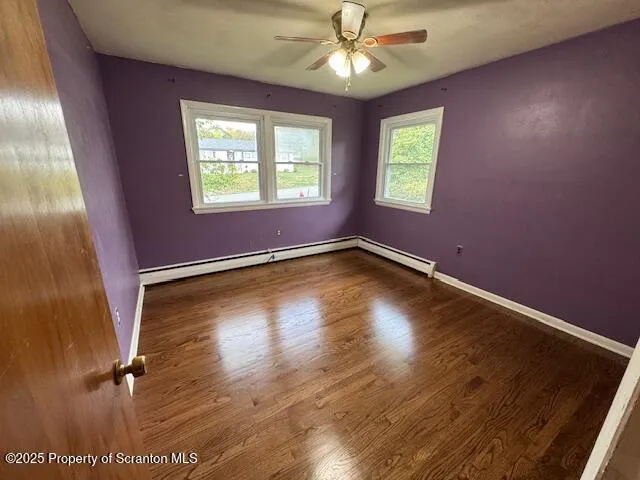 a view of an empty room with a window and wooden floor