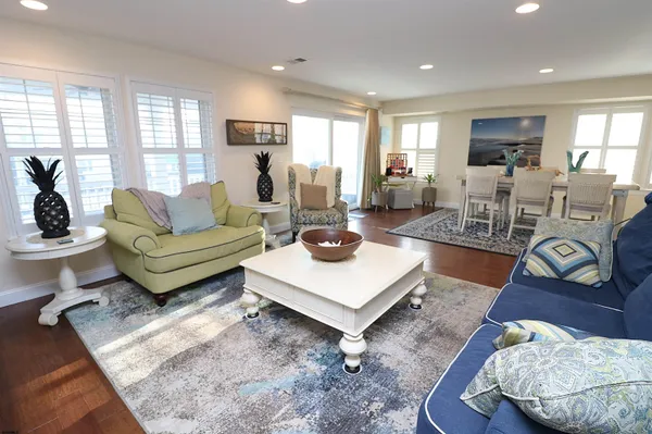 a living room with furniture a rug kitchen view and a large window