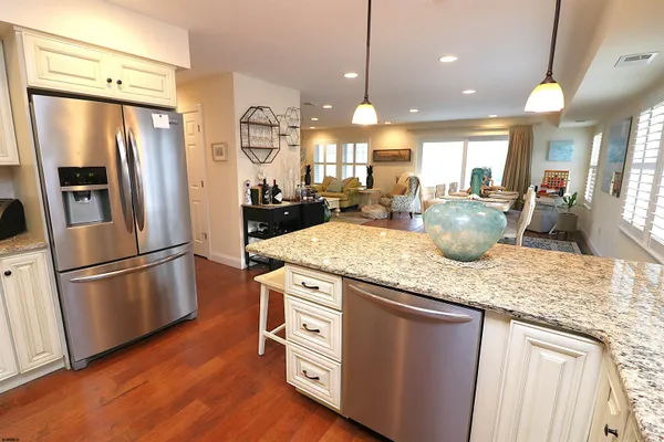 a kitchen with stainless steel appliances granite countertop a refrigerator a sink a stove and a wooden floors