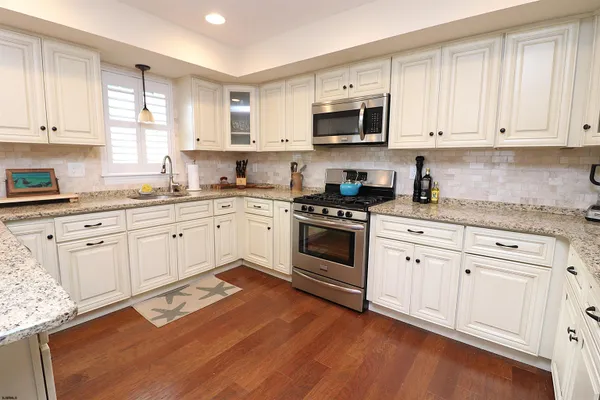 a white kitchen with granite countertop white cabinets and white appliances