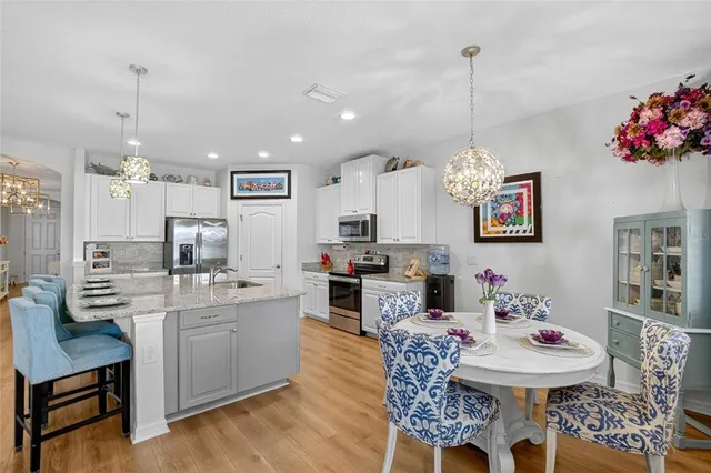 a kitchen with stainless steel appliances kitchen island granite countertop a sink dishwasher and a dining table with chairs