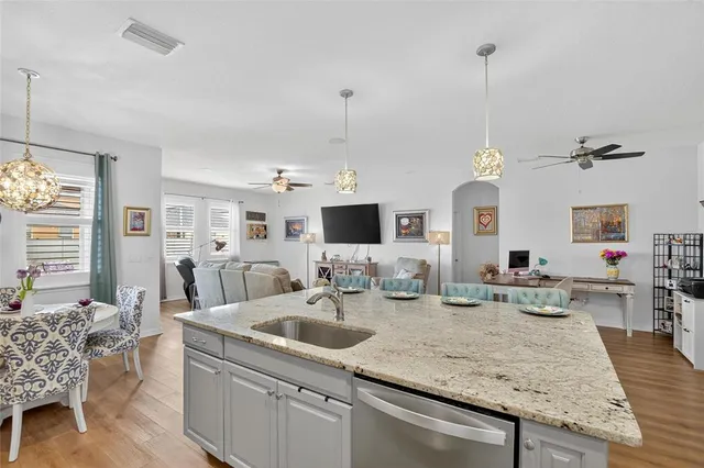 a kitchen with stainless steel appliances kitchen island granite countertop a dining table chairs and a refrigerator