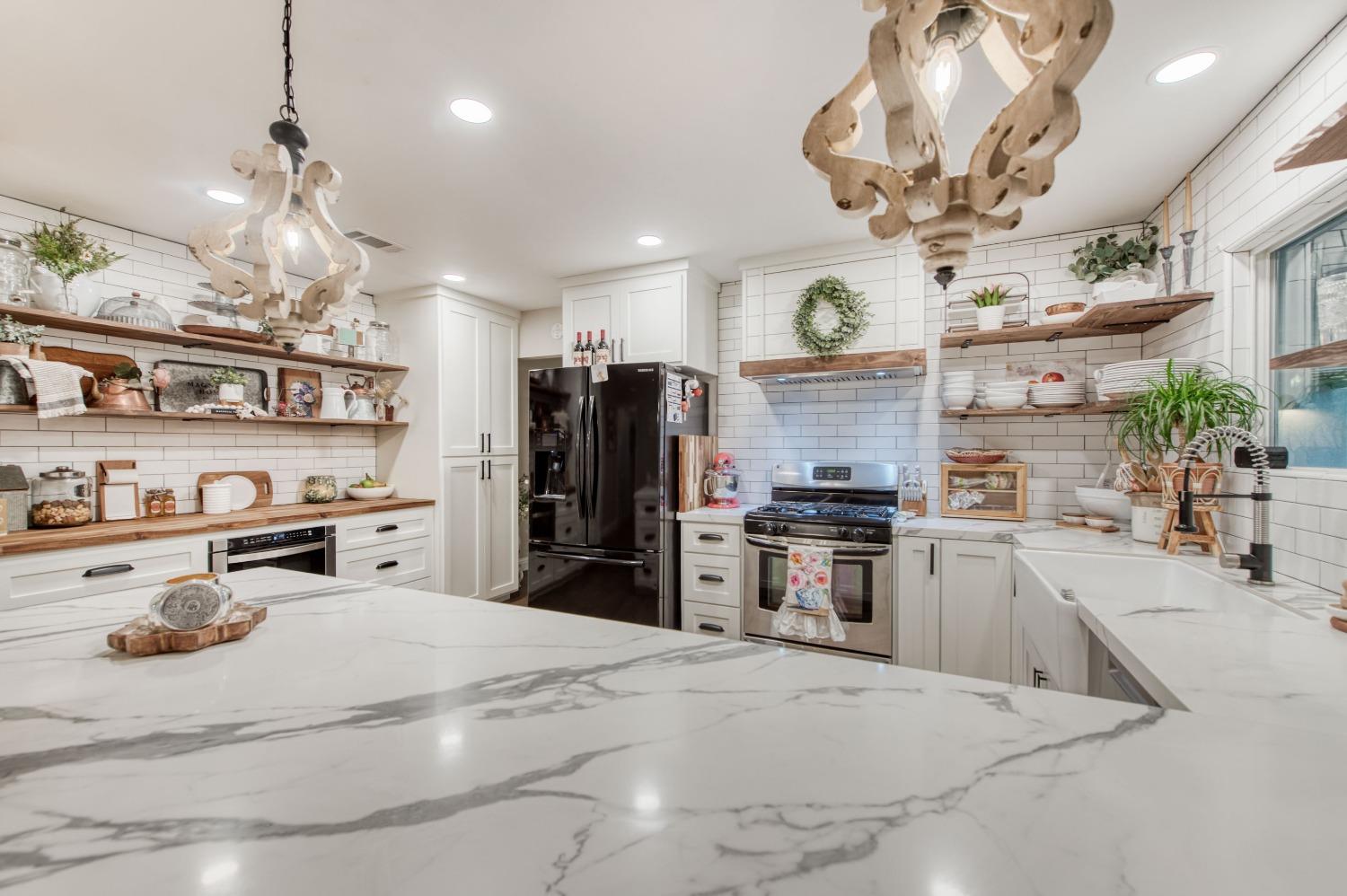 1880 East Cardella Street Firebaugh, CA 93622 - Photo 13 of 42 a kitchen with stainless steel appliances kitchen island granite countertop a refrigerator oven a sink dishwasher a dining table and chairs with wooden floor