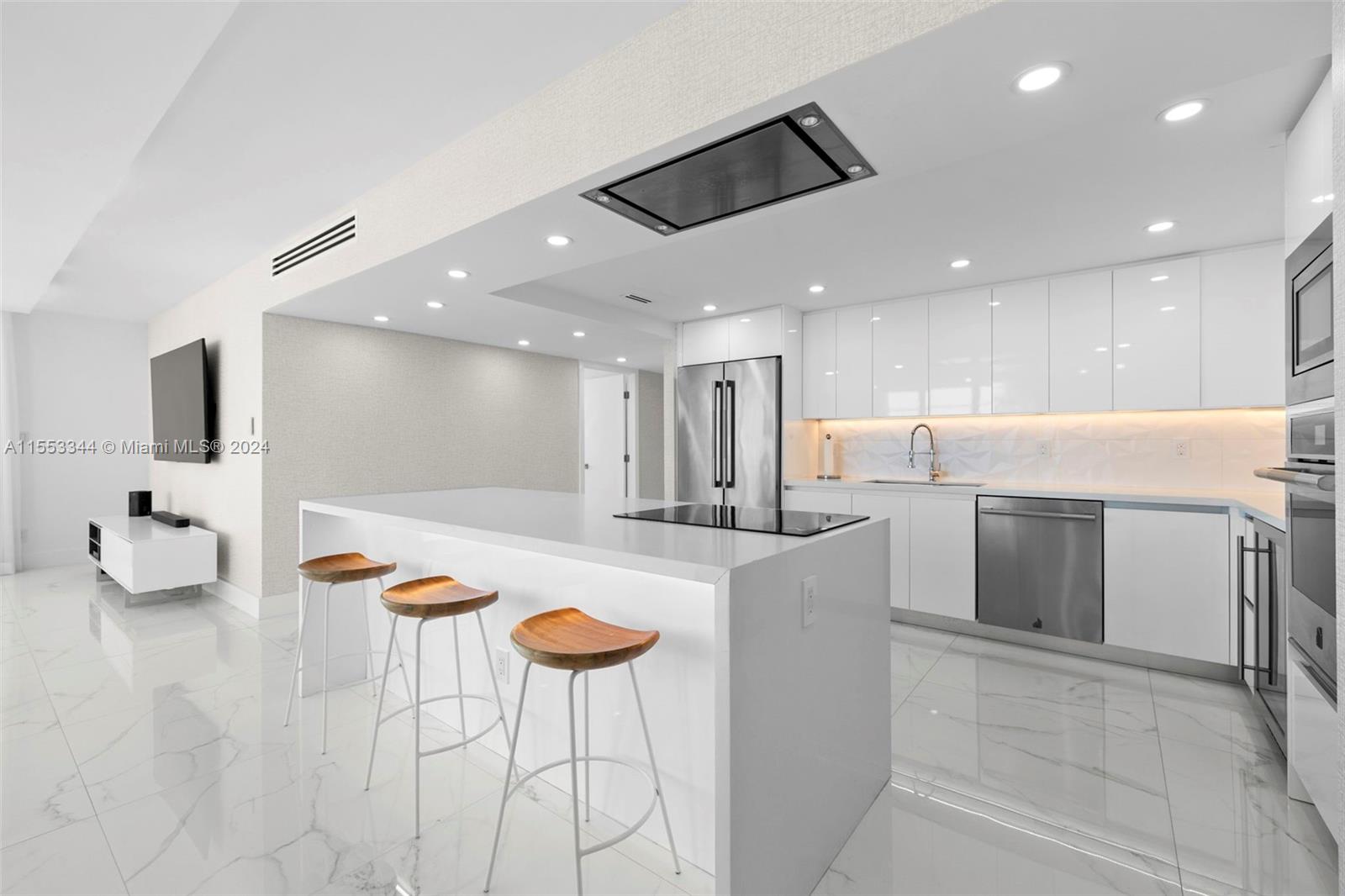 5151 Collins Avenue, Unit 1527 Miami Beach, FL 33140 - Photo 11 of 65 a kitchen with stainless steel appliances kitchen island granite countertop a sink and a refrigerator