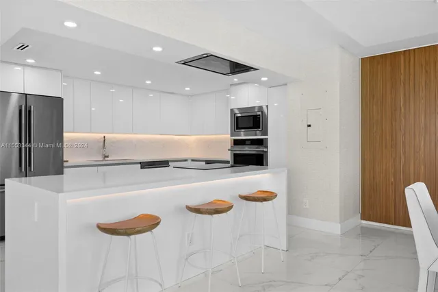 a kitchen with stainless steel appliances kitchen island granite countertop a sink and a refrigerator