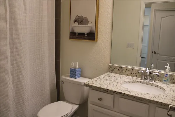 a bathroom with a granite countertop toilet sink and mirror